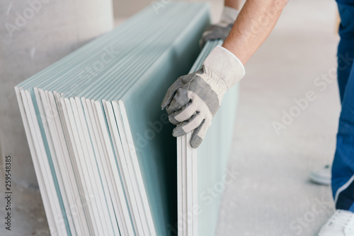 Builder taking a sheet of chip board cladding