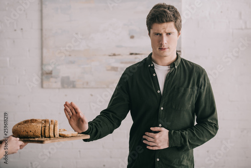 cropped view of woman holding cutting board with bread near handsome man with gluten allergy