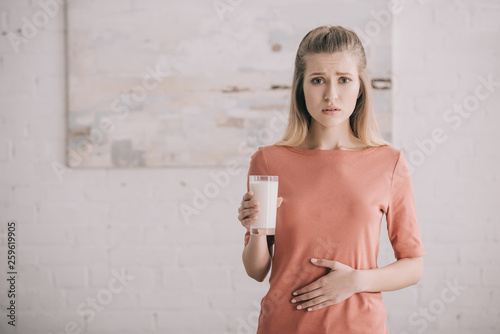 upset woman with lactose intolerance holding glass of milk