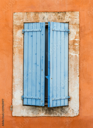 stara niebieska drewniana okiennica na pomarańczowej ścianie - Roussillon, Prowansja, Francja