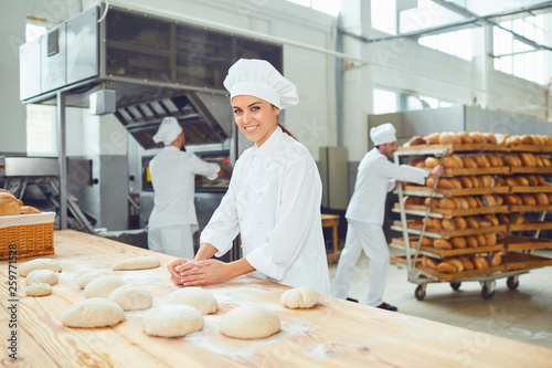 A woman baker smileswith colleagues at a bakery.