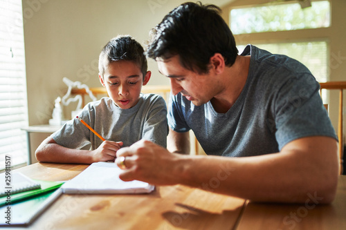 father helping son with homework on table at home