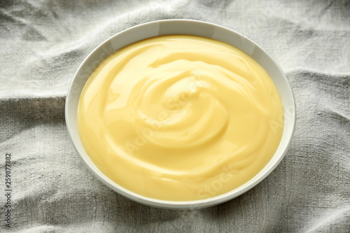 Bowl of vanilla custard on rustic background