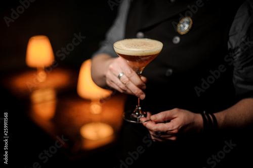 Professional bartender serving cocktail with a whipped cream and grated nutmeg