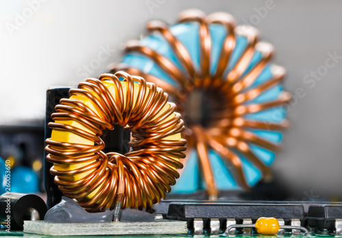 Inductors detail. Copper wire winding. Magnetic ferrite core. Inverter. Beautiful colored coils in dismantled electric power supply unit. Colorful electronic parts. Chips, capacitor. Selective focus.