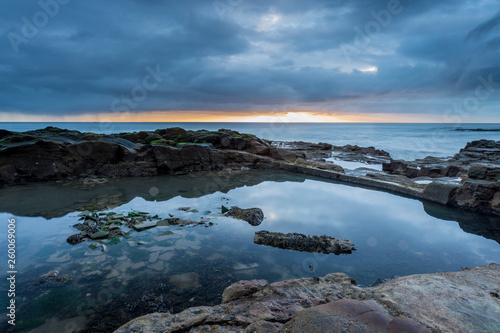 Old and disused bathing pool at Table Rocks, Whitley Bay, on the north east coast of England at sunrise on an overcast day.