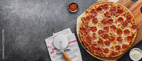 pepperoni pizza on wooden serving board shot top down with copy space composition