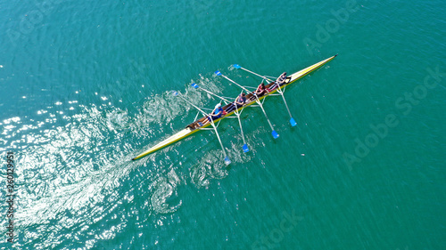 Aerial drone bird's eye view photo of yellow sport canoe operated by team of young team in emerald clear sea