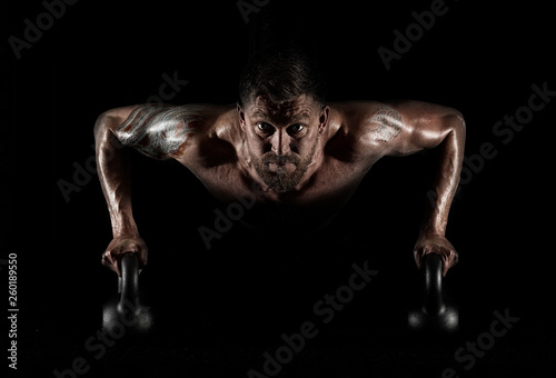 Handsome muscular man doing pushups on kettleball
