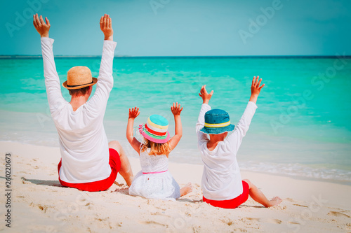 happy dad with son and daughter hands up on beach