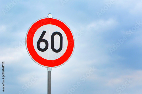 Red round 60km/h speed limit sign on highway in front of blue sky