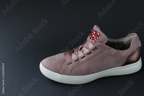 Pink sneakers with jewelry stones on black background