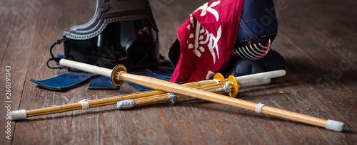 Kendo gloves, helmet and bamboo sword on a wooden surface.