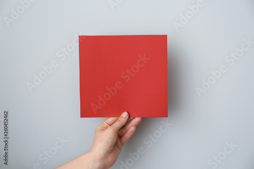 Female hand with blank invitation card on light background