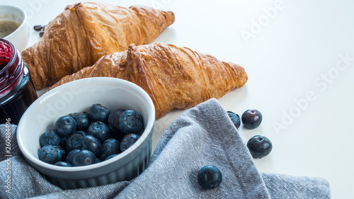 Croissant z owocami i kawą leżące na białym tle