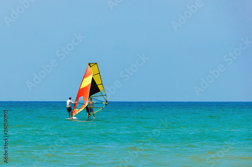 Windsurfing on the background of the sea landscape and clear sky.Two windsurfers men go in for sports, copy space.