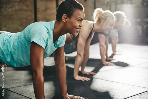 Young woman smiling while doing pushups at the gym