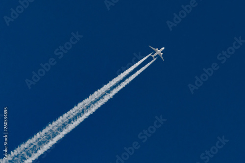 Airplanes leaving contrail trace on a clear blue sky.