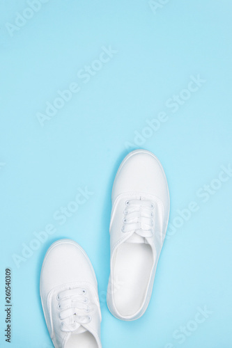 White sneakers on a blue background, copy space.Fashion trend of shoes, shoe shop concept