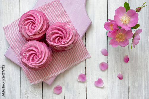 Close up sweet dessert zephyr. Homemade zephyr from currants on a white wooden background with pink flowers.