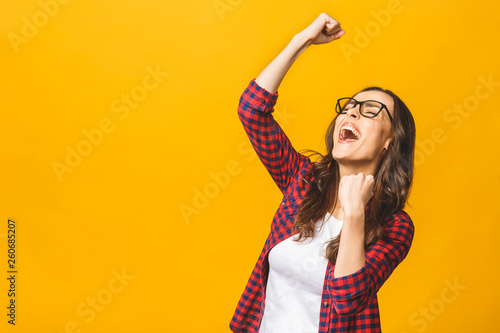 Winning success woman happy ecstatic celebrating being a winner. Dynamic energetic image of multiracial Caucasian Asian female model isolated on yellow background waist up.