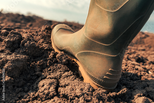 Farmer in wellington rubber boots making first step in field