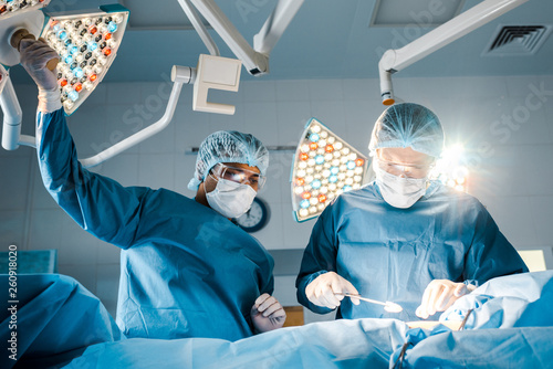 nurse and surgeon in uniforms and medical masks talking in operating room