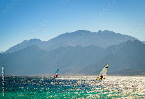 surfers ride in the sea on the background of the rocky coast in Egypt Dahab