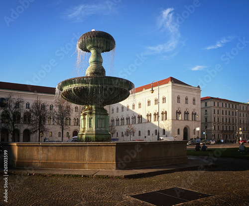 Fountain at Professor Huber square in Munich, Germany with the buildings of the Ludwig Maximilian University