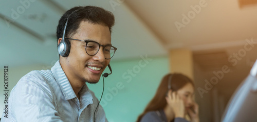 close up asian man call center agent wear headset device and smiling working in operation room with service-mind at desktop table , telemarketing and help desk concept