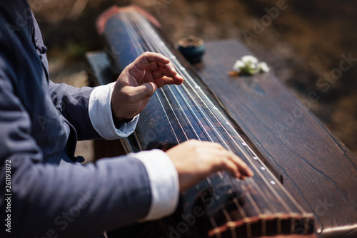 The man is playing the Guqin