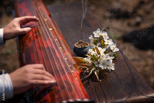 The man is playing the Guqin