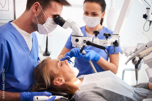 Male dentist working with dental microscope