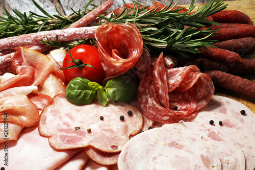 Food tray with delicious salami, pieces of sliced ham, sausage and salad. Meat platter selection.