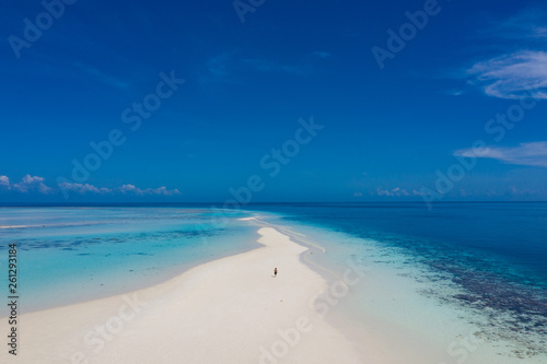 Aerial view of a man walking on the white sand bar in the tropical destination. Hawaii French polynesia Maledives Philippines.