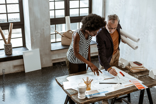 African-American stylish assistant of interior designer helping boss