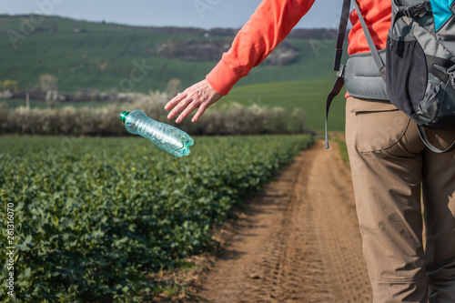 Irresponsible tourist throwing away plastic bottle in nature. Environmental issues