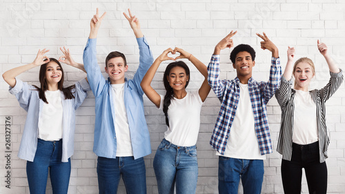 Teen friends gesturing with hands over white wall