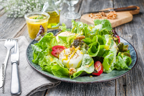 Traditioneller deutscher Sommer Salat mit Blattsalat, Ziegenkäse und Mango Dressing als closeup auf einem Teller mit gedeckten Tisch