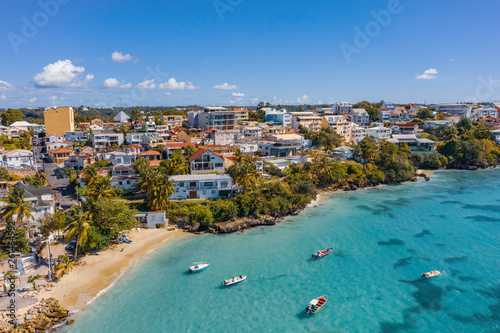 Scenic aerial view of La Datcha beach (Le Gosier plage) in Guadeloupe. Beautiful summer sunny look of small paradise tropical island in Caribbean sea. Several boats and yachts in blue sea.