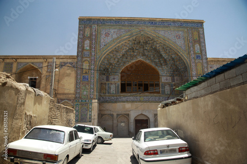 zaniedbany stary i zabytkowy budynek w mieście w iranie z zaparkowanymi przed nim białymi samochodami