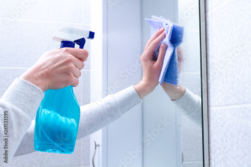 Cleaning and polish mirror with rag and spray in bathroom at home. Housekeeping and cleaning service. Clean house, cleanliness