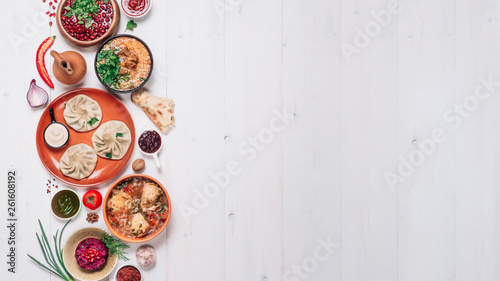 View from above of georgian cuisine on white wooden table. Banner traditional georgian food - khinkali, kharcho, chahokhbili, phali, lobio and local sauces. Top view. Copy space for text