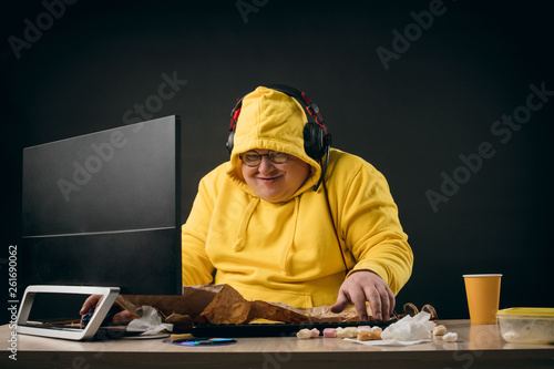 Funny guy in yellow hoody getting pleasure from online games. close up photo. isolated black background.studio shot. computer hacker making up a new programme.crime concept