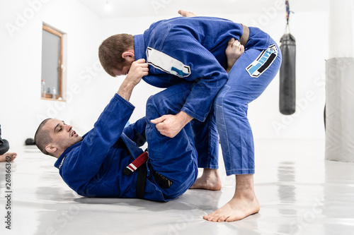 Two young BJJ Brazilian Jiu jitsu Athlete fighters training sparing technique at the academy fight