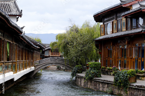 A view of a street with a bridge, houses, flowers and canals of the ancient city of Lijiang, Yunnan, China