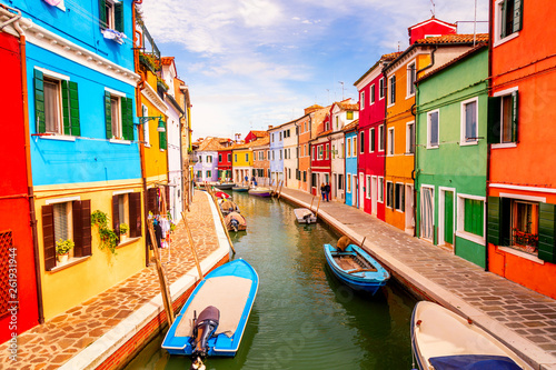 Colorful houses in Burano near Venice, Italy with boats, canal and tourists. Famous tourist attraction in Venice.
