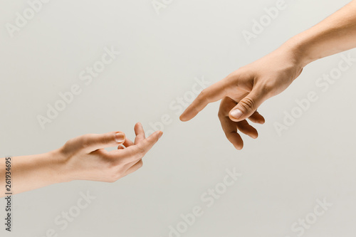 Moment of weightless. Two male hands trying to touch like a creation of Adam sign isolated on grey studio background. Concept of human relation, community, togetherness, symbolism, culture and history