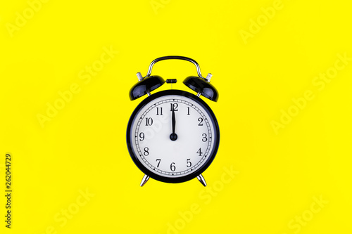 black vintage alarm clock on color background