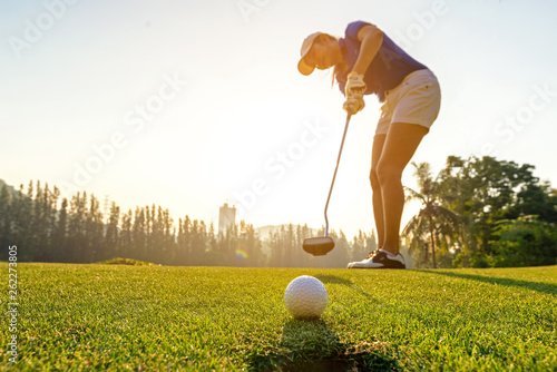 Sport Healthy. Golfer asian sporty woman focus putting golf ball on the green golf on sun set evening time. Healthy and Lifestyle Concept